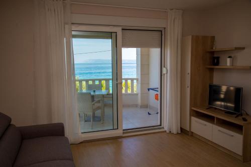 uma sala de estar com uma porta de vidro deslizante e vista para o oceano em Waterfront Apartments - Tucepi em Tučepi