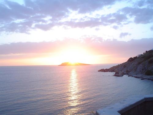 a sunset over the ocean with a small island in the distance at Alkyonis Apartments in Panormos Kalymnos