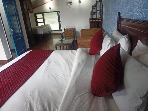 a bedroom with a bed with red and white pillows at Manu Maharani Regency in Nainital