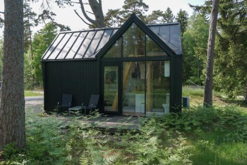 a black cabin with glass doors in a forest at Männikäbin Tiny House 
