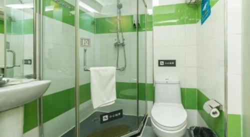 a green and white bathroom with a toilet and a sink at 7 Days Inn Changchun Zhengyang Street Changchun Park Branch in Changchun