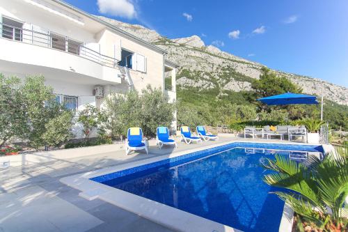 a swimming pool with blue chairs and a house at Villa Levanda in Makarska