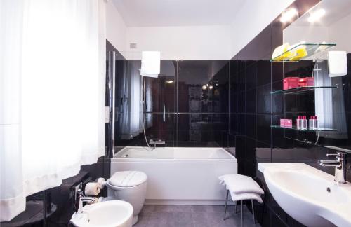 a bathroom with a tub and a toilet and a sink at Hotel Carlton in Ferrara