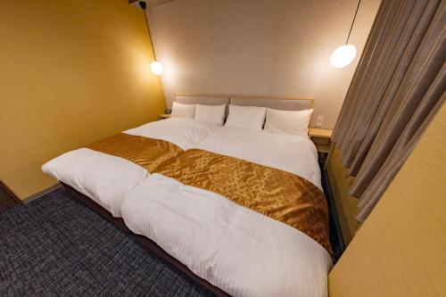 a bedroom with two beds with white sheets and gold blanket at MADOKA Kyoto station west in Kyoto