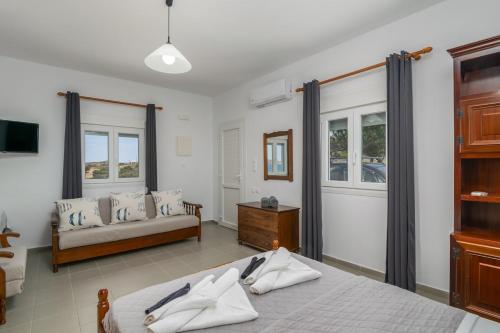 a bedroom with two beds and a couch and windows at Kondylis Cottage in Provatas