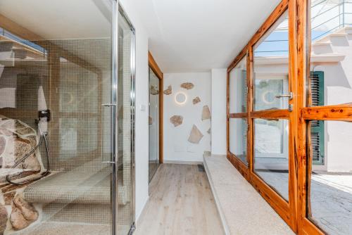 a glass pivot door in a room with a walk in shower at VILLA AMIRA Porto Cervo con vista Mozzafiato sul Mare,Piscina Privata,WELLNESS & SPA in Liscia di Vacca