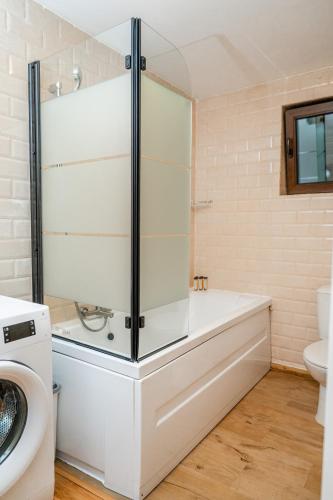 a bathroom with a tub and a washing machine at Ceahlau Cozy House with Terrace, Bbq & Free Parking in Braşov