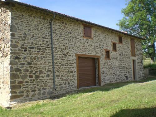 - un bâtiment en pierre avec une porte et un garage dans l'établissement Maison de campagne en Auvergne, à Champagnac-le-Vieux