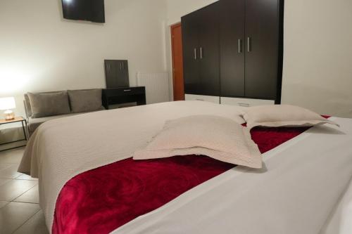 a large white bed with a red blanket on it at Διαμερίσματα Μαριάννα in Drama