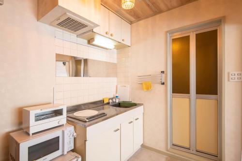 a small kitchen with a sink and a microwave at Lazurite GUESTHOUSE Pear Field in Inagi