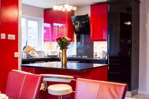 a kitchen with red cabinets and a vase of flowers on a counter at Spacious Three Bedroom Detached Bungalow in Dundee with large Gardens in Dundee