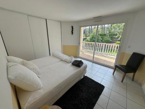 une chambre avec un lit, une chaise et une fenêtre dans l'établissement VILLA Magnifique GOLF & OCEAN, à Lacanau