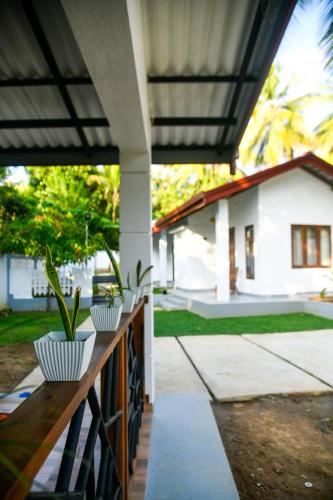 a porch with two potted plants on a wooden railing at The Wild Side Cottage in Udawalawe
