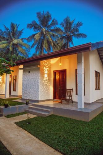a house with palm trees in the background at The Wild Side Cottage in Udawalawe