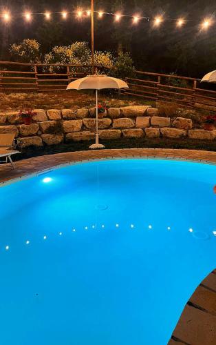 a blue swimming pool with an umbrella at Rustic Country House in Smirra