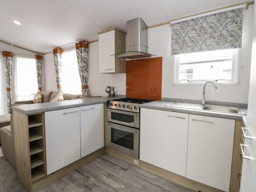 a kitchen with white cabinets and a sink and a stove at Ash in Denny