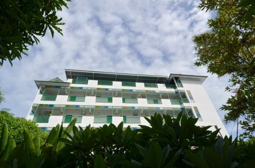 a white building with green windows and trees at Makmai Villa - Rayong in Ban Phe