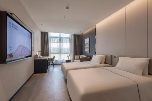 a hotel room with two beds and a projection screen at Atour Hotel Xiamen Huli Powerlong International in Xiamen