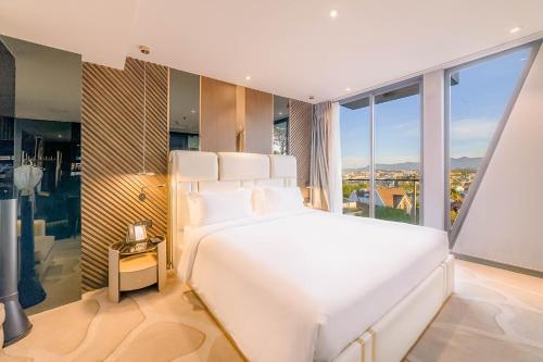 a bedroom with a large white bed and large windows at New Century Dalat Hotel in Da Lat