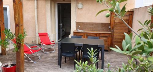 une table noire et des chaises sur une terrasse dans l'établissement Apartment with large terrace, ground floor, à Narbonne