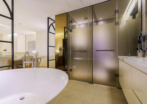 a bathroom with a tub and a glass shower at Hotel The Designers Incheon in Incheon