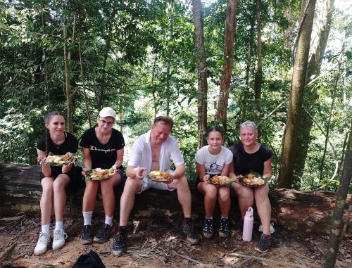 a group of people sitting on a log in the woods at SEE BUKIT LAWANG Homestay & Tours in Bukit Lawang