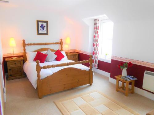 a bedroom with a wooden bed with red pillows at The Osprey in Kingussie