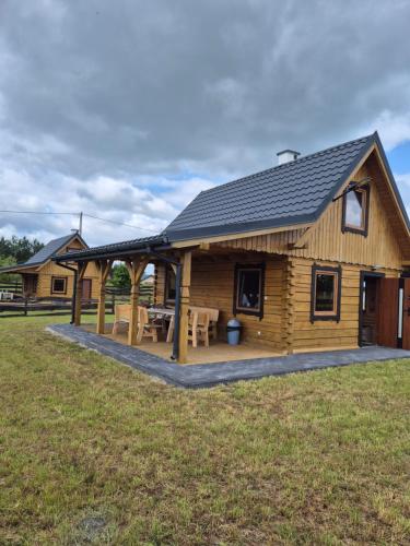 a log cabin with a picnic table in a field at Domek z Bala Brajniki- całoroczny in Brajniki