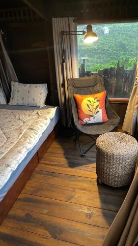 a bed and a chair in a room with a window at Đen Hill Home The Wooden in Ðại Lào