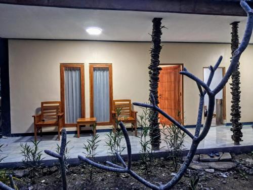 a house with wooden doors and chairs in a yard at Lonthar B&B - Adults Only in Riung