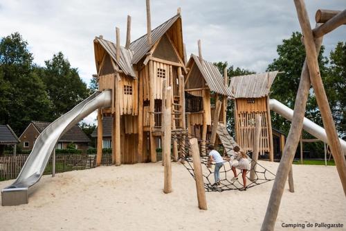 two people playing on a playground in the sand at Sola Lodge - Luxe chalet in natuur Overijssel in Mariënberg