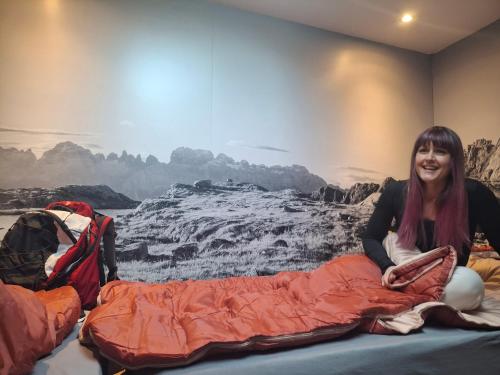 a woman sitting on a bed in front of a painting at Inner Holiday Dolomites 5 in Dimaro