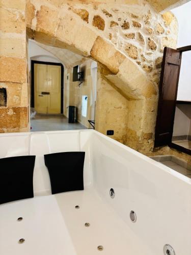a bath tub in a room with a stone wall at la nicchia, relax room & salento stay in Manduria
