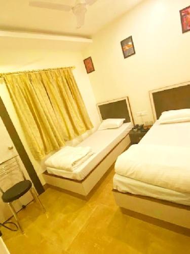 a bedroom with two beds and a chair in it at Noble Nook Place in Shillong