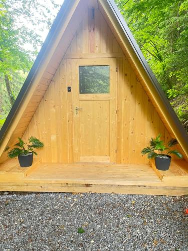 a wooden building with a door and two potted plants at Glamping - domačija Lamperček in Velenje