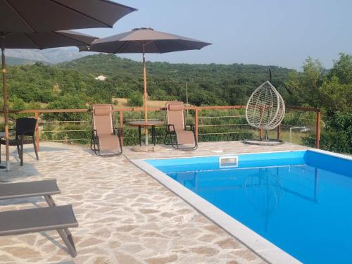 a pool with chairs and a table and an umbrella at Old House Piperi in Podgorica