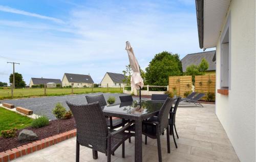Un patio con una mesa y sillas y una sombrilla. en Maison Agréable Près Etretat, en Beaurepaire