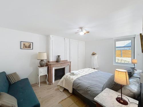 une chambre avec un lit, un canapé et une cheminée dans l'établissement Le Lies - Appartement proche de la mer, à Salles-d'Aude