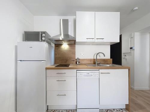 La cuisine blanche est équipée d'un évier et d'un réfrigérateur. dans l'établissement Le Lies - Appartement proche de la mer, à Salles-d'Aude