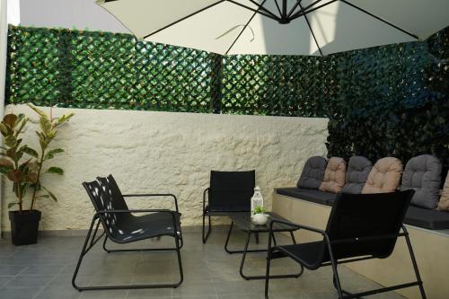 a patio with chairs and a table with an umbrella at Casa di Keti - Modern Home with Private Yard ,3 Min to the Beach in Chania