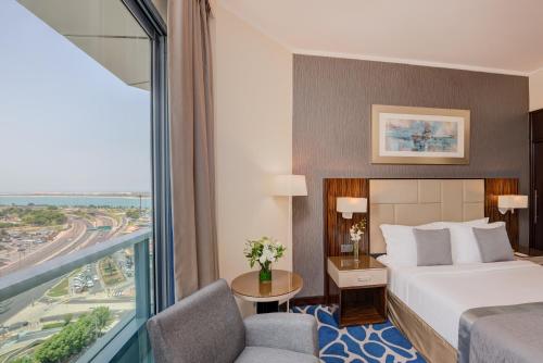 um quarto de hotel com uma cama e uma janela grande em Hawthorn Extended Stay by Wyndham Abu Dhabi City Center em Abu Dhabi