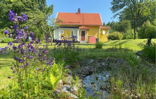 a yellow house with a garden with purple flowers at 2 Bedroom Stunning Home In Broakulla in Broakulla