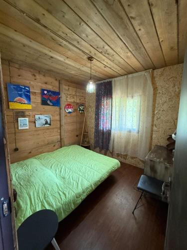 a bedroom with a green bed in a wooden room at Welcome to Tamara Cottage in Tba