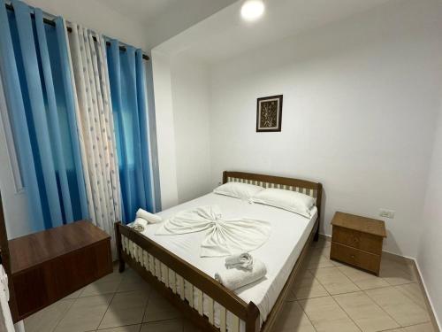a bedroom with a bed with blue curtains and a table at Apartment Radhima in Vlorë