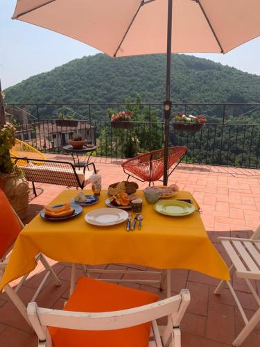 a table with a yellow table cloth and an umbrella at La Casa Stregatta in Sassetta