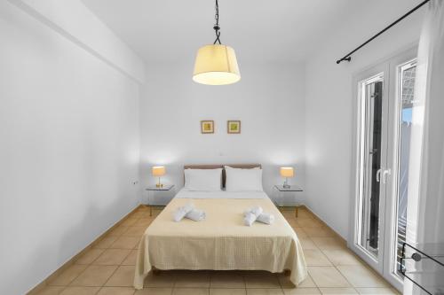 a white bedroom with a bed and two lamps at Tzane Studios & Apartments - Steps away from Golden Beach in Chrissi Akti