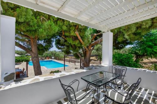 a patio with a table and chairs and a swimming pool at Tzane Studios & Apartments - Steps away from Golden Beach in Chrissi Akti