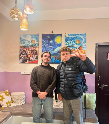 two men standing in a room with paintings on the walls at Thikana by Mulaqat in Siliguri