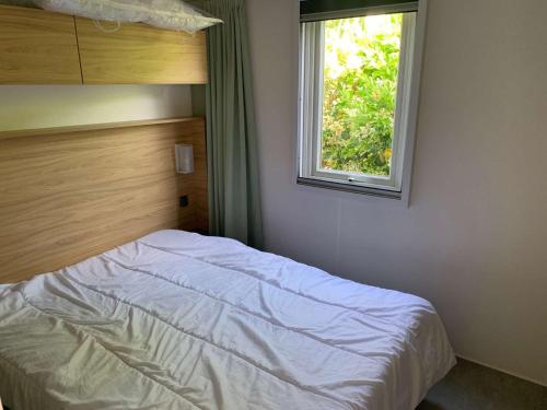 un lit dans une chambre avec une fenêtre dans l'établissement Le parc des roselieres 40 Saint Hilaire de Riez, à Saint-Hilaire-de-Riez