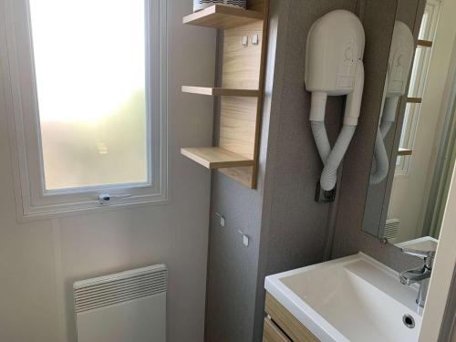 une petite salle de bains avec lavabo et téléphone. dans l'établissement Le parc des roselieres 40 Saint Hilaire de Riez, à Saint-Hilaire-de-Riez